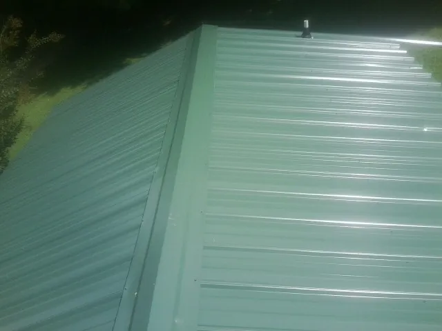 New green metal panels meeting at the ridge of a roof — Flat Roof Repair work by our crew in Warrenville