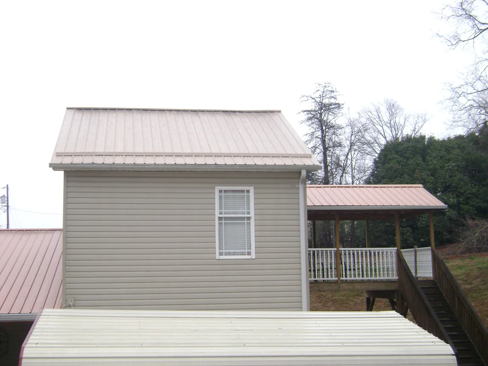 Tan metal roofs on a two story addition and attached porch, from a Roof Replacement job in Warrenville