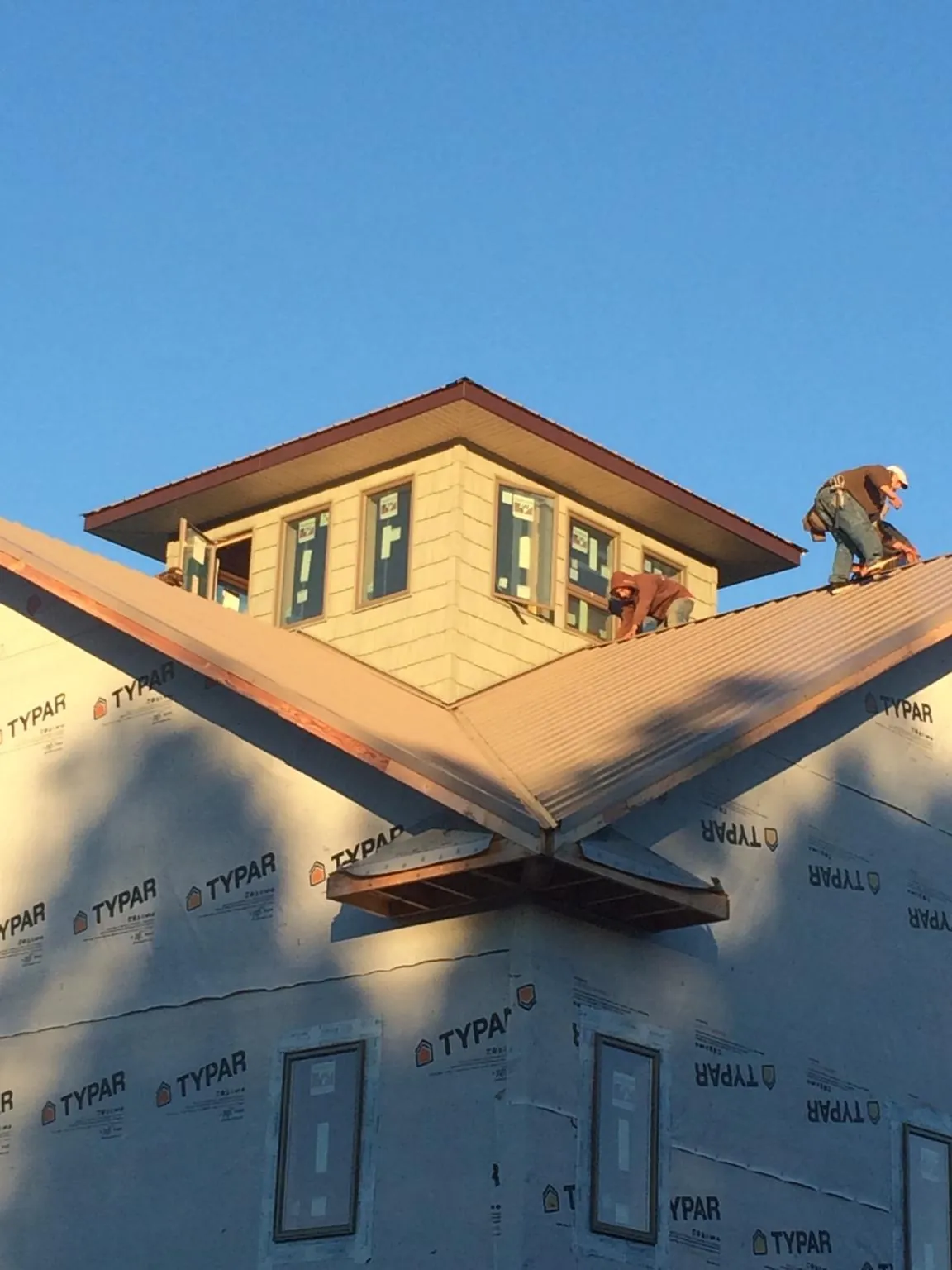 Roofers working around a rooftop cupola on a new metal roof at sunset — Roof Waterproofing in Warrenville by Roofing Brothers